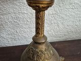 a brass candle holder on a wooden table with a white wall in the background