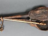 un vieil instrument en bois muni d'un manche en bois, posé sur une surface grise