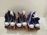 Quatre paires de Converse bleues sont alignées sur une caisse en bois.