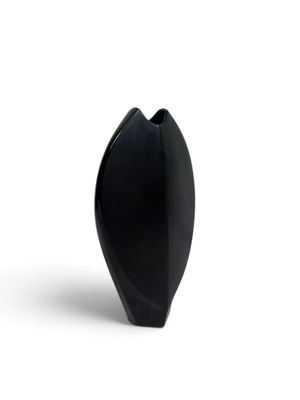 un vase noir posé sur une surface blanche