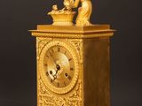 a gold clock sitting on a wooden table with a black background