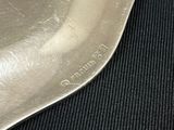 a silver plate with a spoon on it on a black table