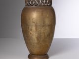 un vase doré posé sur une table blanche