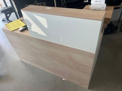 un comptoir d'accueil blanc et en bois dans une grande pièce