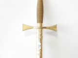a close up of a sword hanging on a wall near a white wall