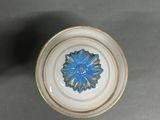 a blue flower on a white plate on a table