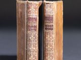 two old books sitting on top of a table next to each other