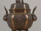 a bronze urn with a dog on top of it
