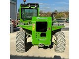 a green tractor with large tires parked in a parking lot