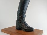 une statue représentant une paire de bottes posée sur un socle en bois