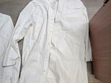 une chemise blanche posée par terre à côté d'une armoire en bois