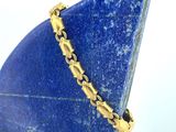 bracelet plaqué or posé sur un socle en pierre bleue avec un fond blanc