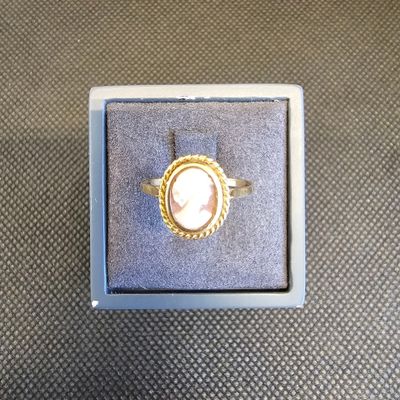 une bague sur laquelle est gravée l'image d'une femme, dans une boîte