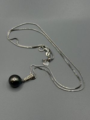 un gros plan d'un collier composé d'une perle noire montée sur une chaîne en argent