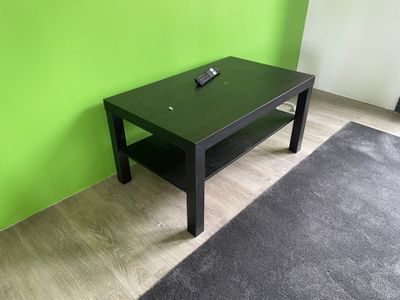 une table basse noire sur laquelle est posée une télécommande