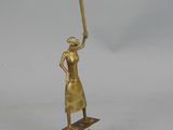 brass figurine of a woman holding a baseball bat on a stand