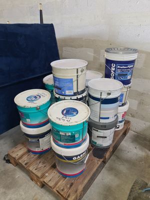 several buckets of paint sitting on top of a pallet in a room