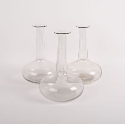trois vases en verre transparent posés sur une surface blanche