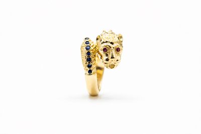 une image représentant une bague en or ornée d'une tête de lion aux yeux de saphir bleu