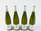 three bottles of white wine are lined up on a white surface