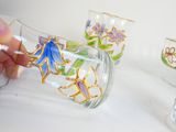 a person that is painting a glass vase with flowers on it