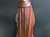 a bronze statue of a woman in a robe on a wooden table