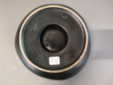 a black vase sitting on a table with a tag on it