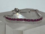 un bracelet en argent orné de pierres roses, posé sur une table