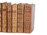 several old books are lined up in a row on a white surface