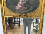 a man standing in front of a mirror with a painting on it