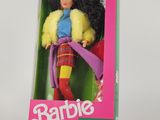 une poupée Barbie dans une boîte, posée sur une surface blanche avec un fond rose