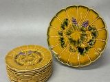 yellow and green plates with purple flowers on them sitting on a white surface
