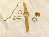 une montre-bracelet en or, une bague et d'autres bijoux posés sur un drap blanc