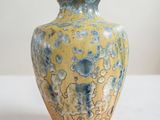 un vase jaune et bleu posé sur une table blanche