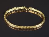 gros plan d'un bracelet en or sur une surface noire