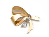 une image représentant une broche en forme de nœud, en or et diamants