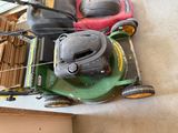 two lawn mowers sitting on the floor next to each other