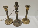 trois bougeoirs anciens en laiton exposés dans une vitrine