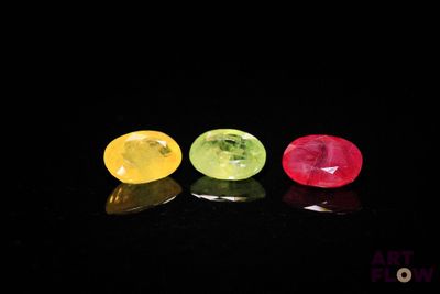 trois gemmes de couleurs différentes alignées sur une surface noire