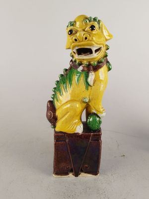 figurine de chien jaune assise sur une boîte et portant un collier vert