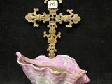 un gros plan d'une croix posée sur un coquillage rose