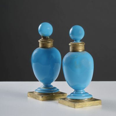 une paire de vases en verre bleu avec des socles en laiton, posés sur une surface blanche