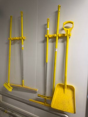 a lot of brooms hanging on the wall in the bathroom