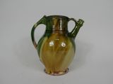 a green and yellow vase on a white surface
