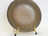 a brown plate on a gold stand on a white surface