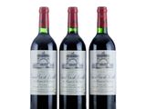 trois bouteilles de vin rouge posées l'une à côté de l'autre sur une surface blanche