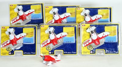 six petits avions jouets sont alignés en rang sur une surface blanche