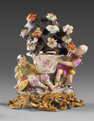 deux figurines d'enfants assis sur une table avec un panier de fleurs