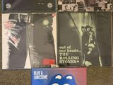 the rolling stones albums are sitting on a carpeted floor