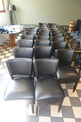 des rangées de chaises noires dans une pièce au sol en damier
